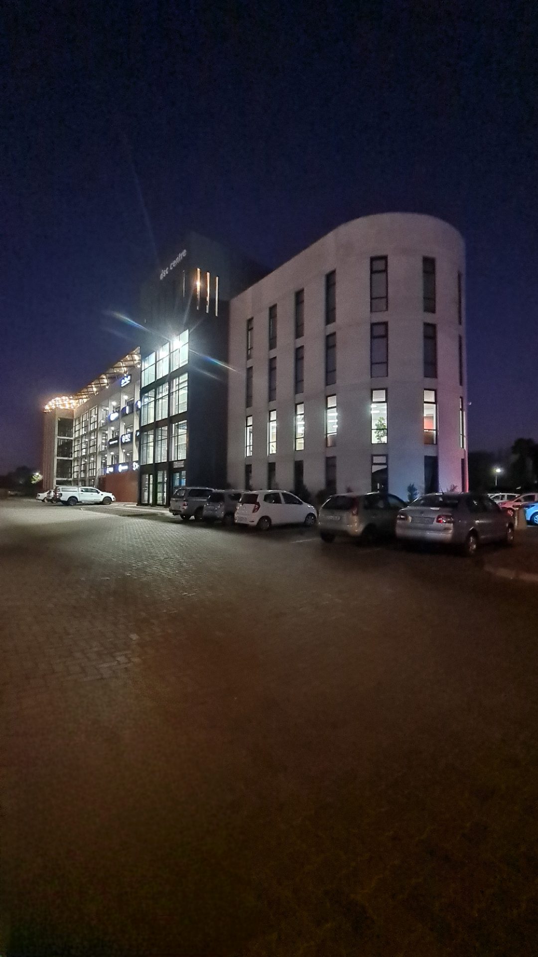 The Heights at night, warm light glowing from the curved facade