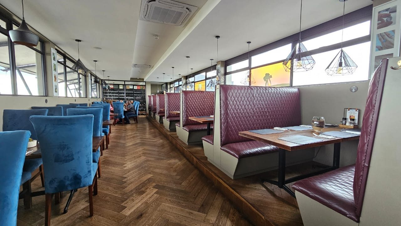 Burgundy quilted booths and blue velvet chairs on a herringbone floor